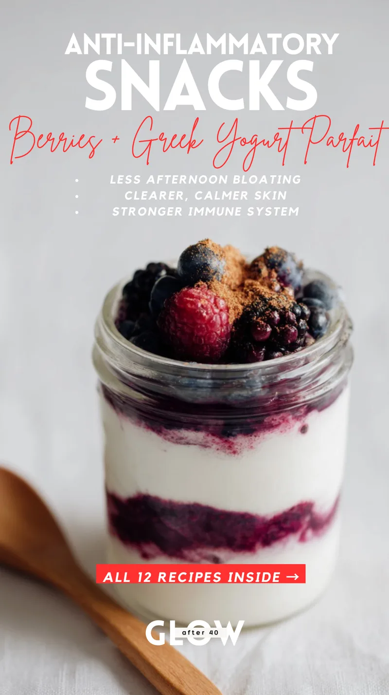 A glass jar filled with layers of white Greek yogurt and dark purple mixed berry compote, topped with fresh raspberries, blueberries, blackberries, and a dusting of cinnamon against a white background. Text overlays highlight anti-inflammatory snack benefits including less afternoon bloating, clearer skin, and a stronger immune system.